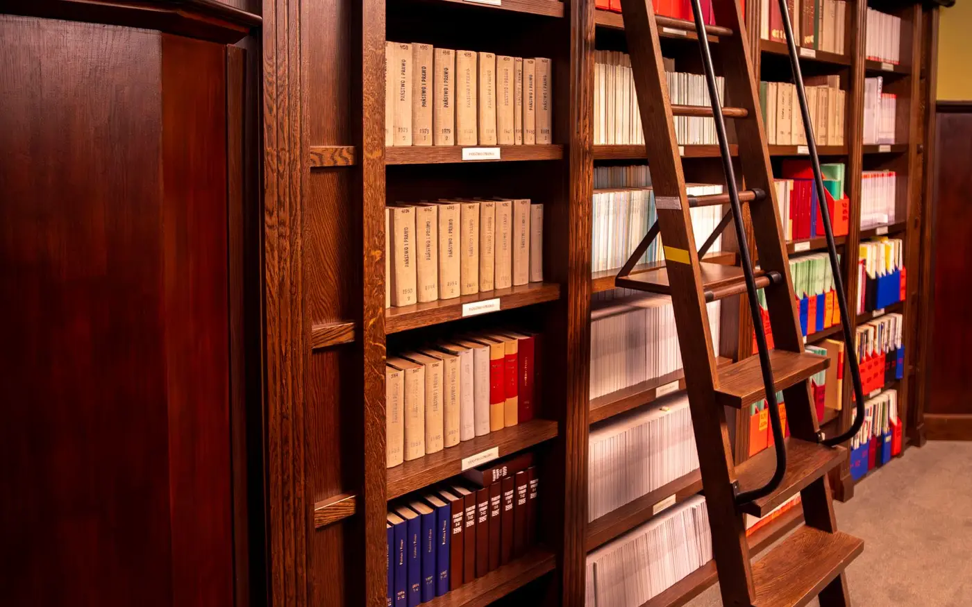 Wooden library shelves of bound volumes with a rolling ladder